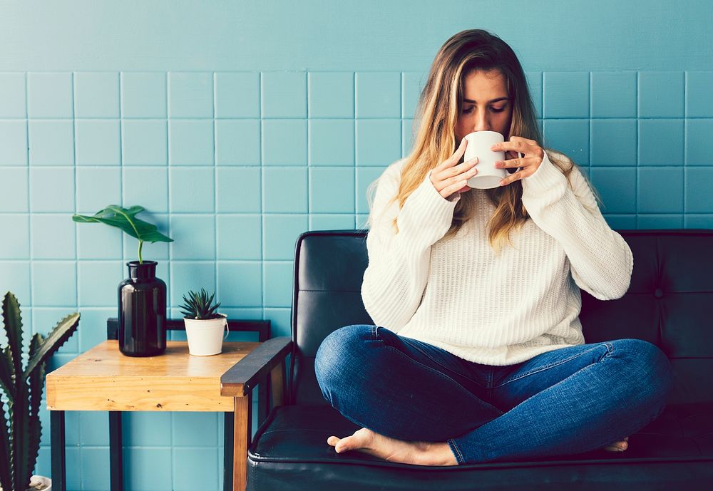 Girl drinking coffee by a blue wall