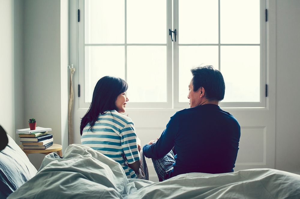 Asian couple talking together in bed
