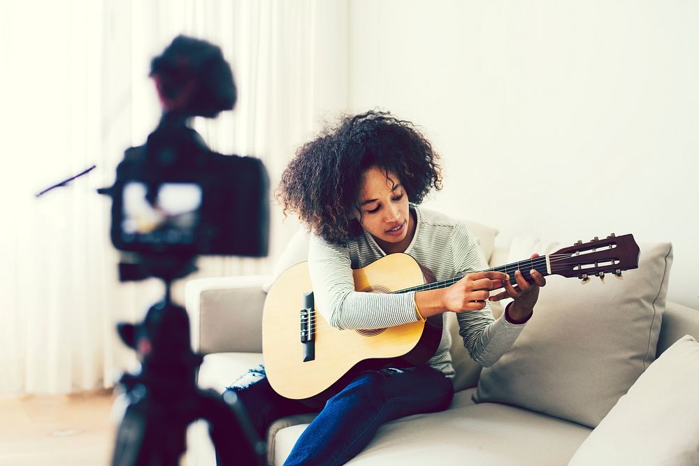 Female vlogger filming herself playing a guitar