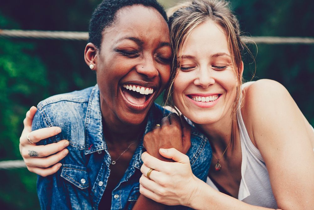 Two girl friends laughing and embracing each other