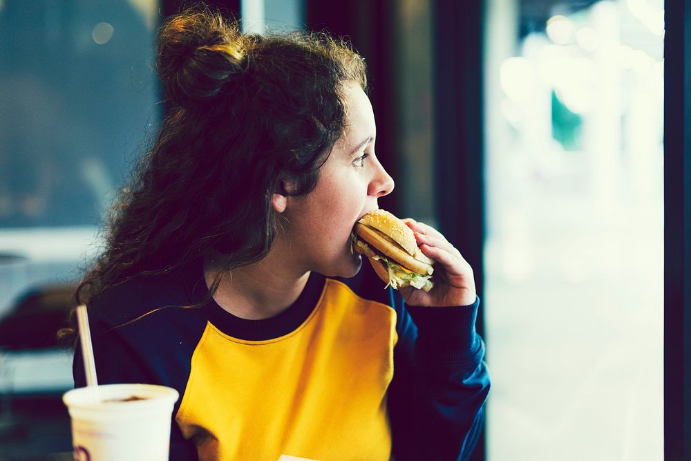 Close up of teenage girl eating a hamburger