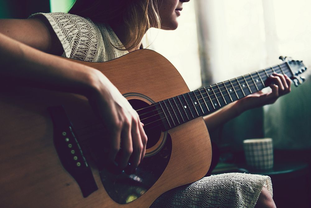 Girl playing an acoustic guitar alone