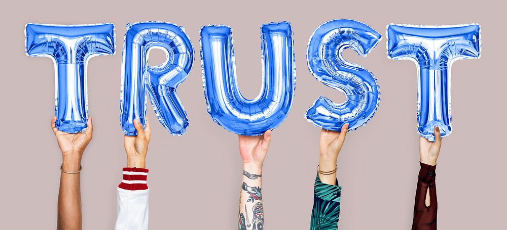 Hands holding trust word in balloon letters