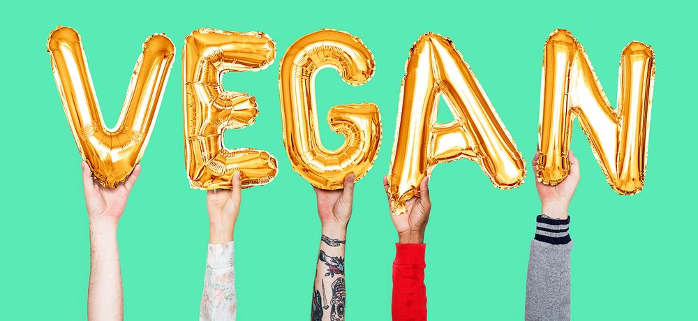 Hands holding vegan word in balloon letters