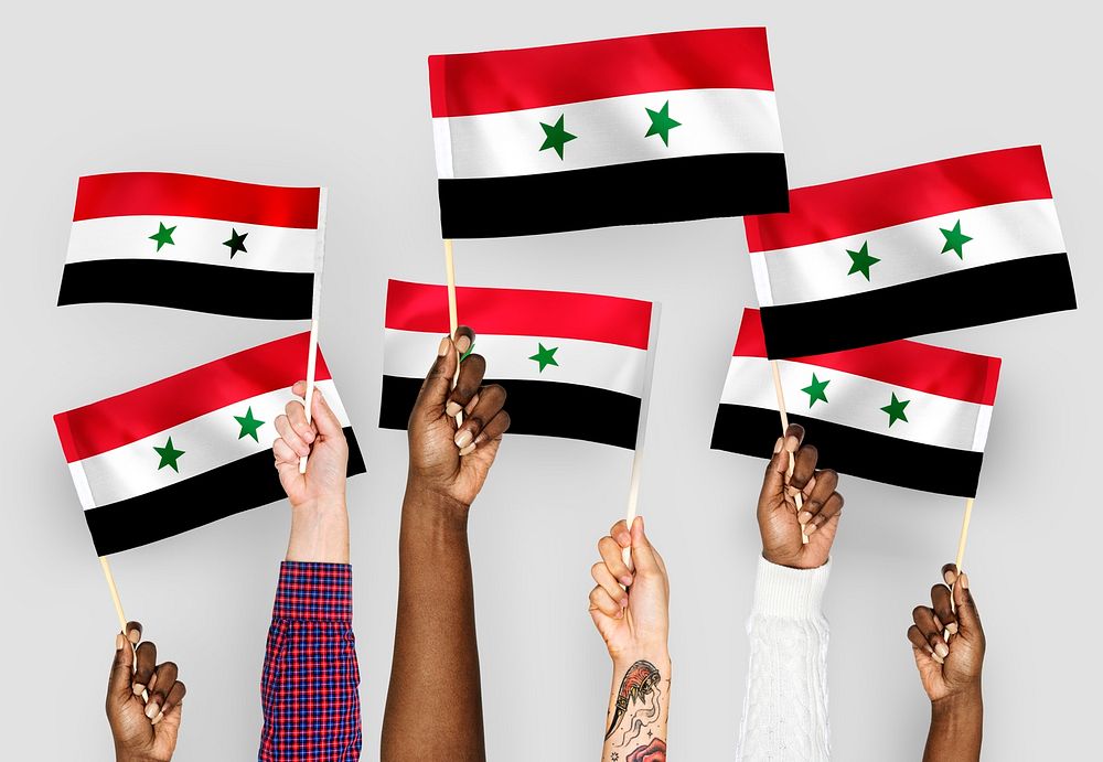 Hands waving flags of Syria