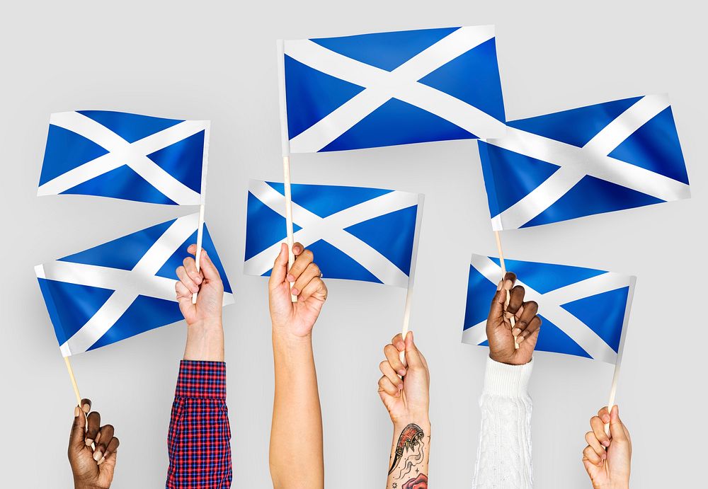 Hands waving flags of Scotland