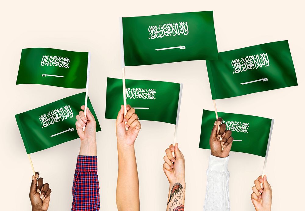 Hands waving the flags of Saudi Arabia