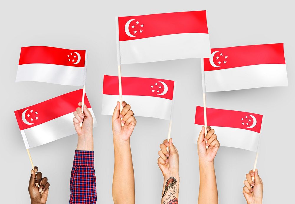 Hands waving flags of Singapore