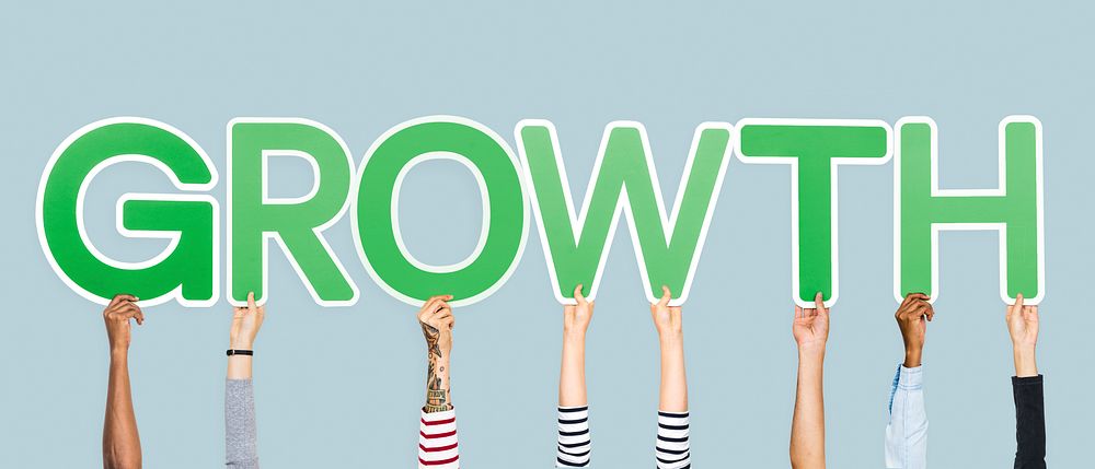 Hands holding up green letters forming the word growth