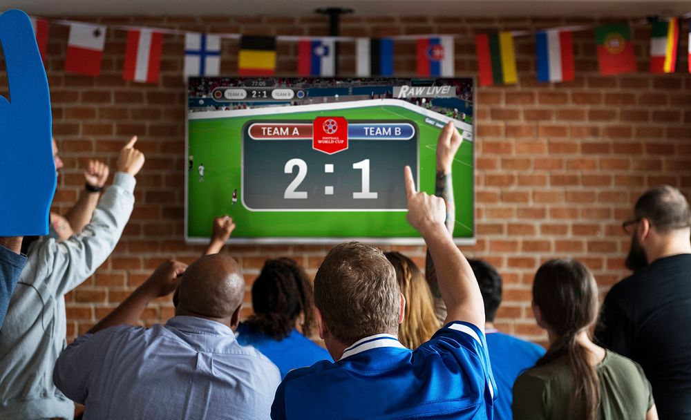 Cheerful supporters watching football at the pub