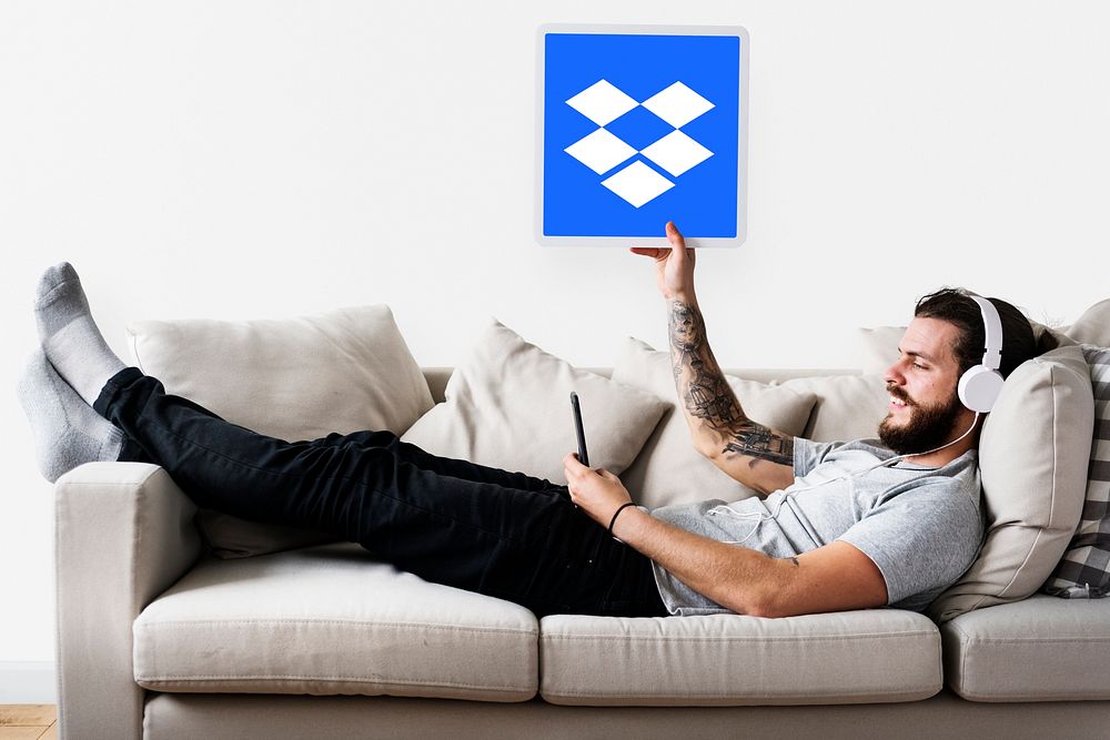 Man showing a Dropbox icon on a sofa