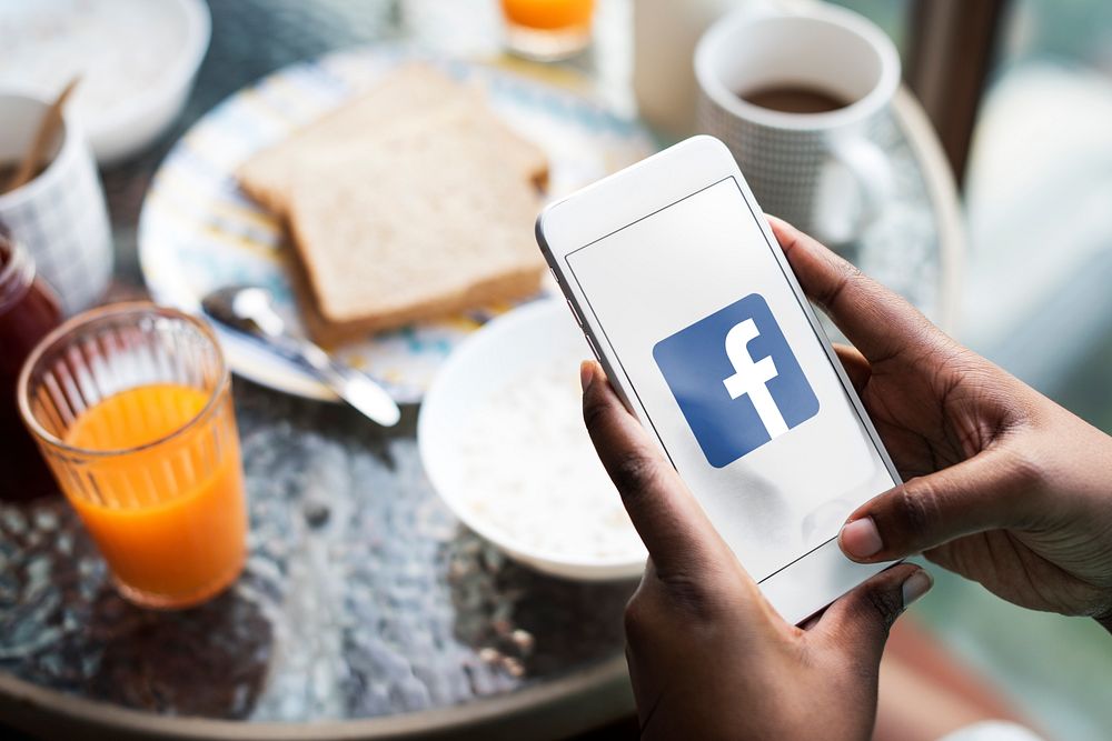 Woman using Facebook while having breakfast. BANGKOK, THAILAND, 1 NOV 2018.