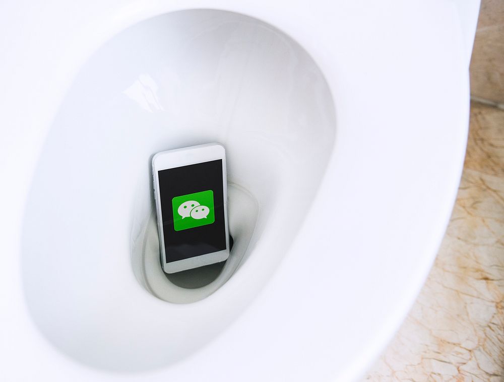WeChat logo showing on a phone in a toilet bowl. BANGKOK, THAILAND, 1 NOV 2018.