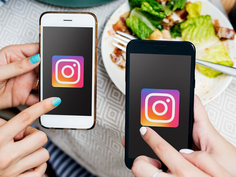 Friends using Instagram on mobile phones in a restaurant. BANGKOK, THAILAND, 1 NOV 2018.
