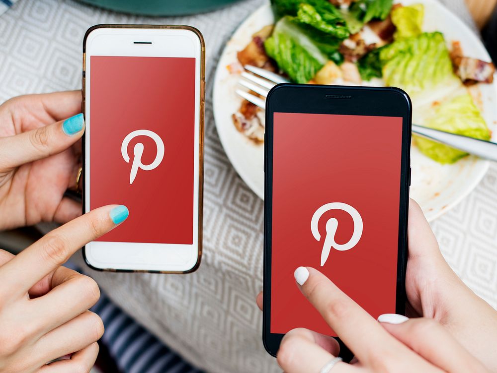 Friends using Pinterest on mobile phones in a restaurant. BANGKOK, THAILAND, 1 NOV 2018.