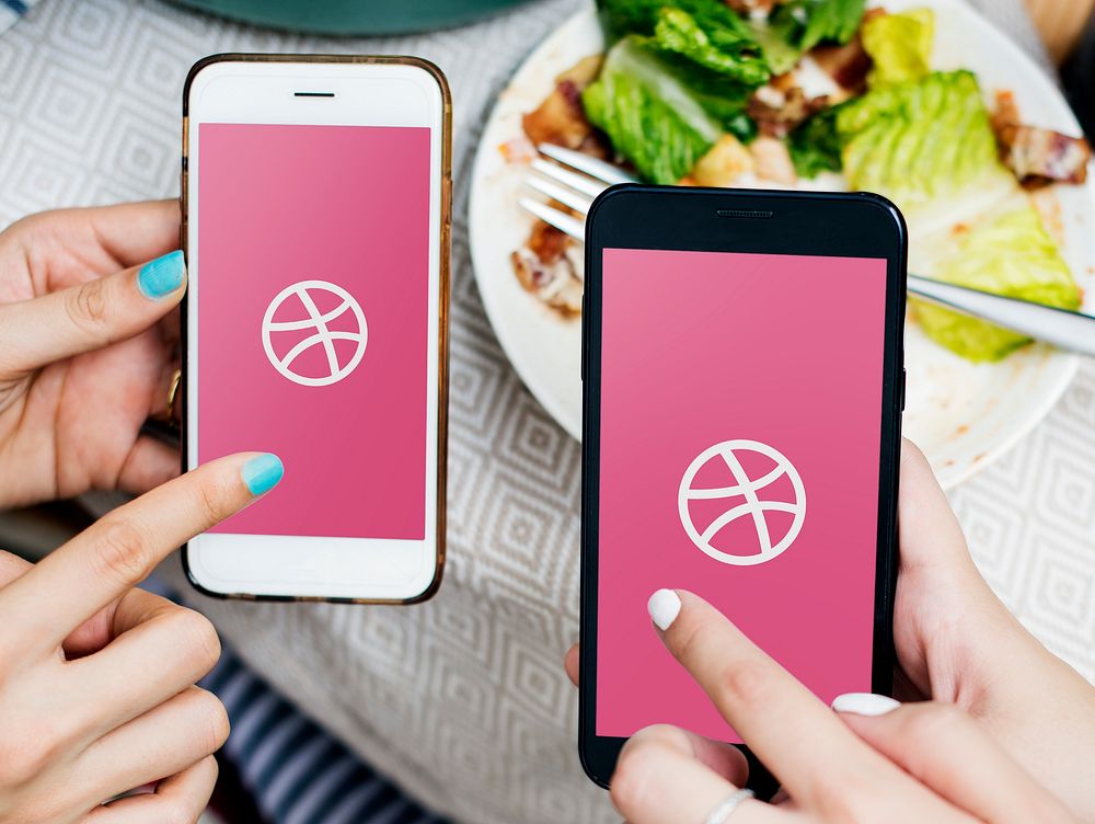 Friends using Dribbble on mobile phones in a restaurant. BANGKOK, THAILAND, 1 NOV 2018.