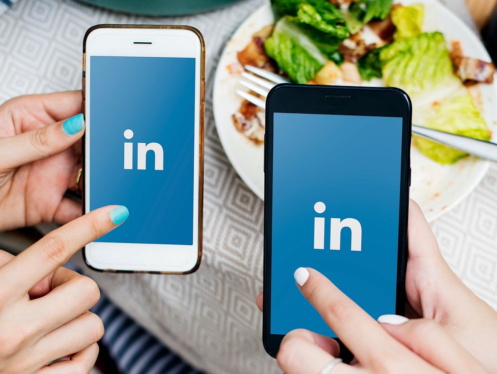 Friends using LinkedIn on mobile phones in a restaurant. BANGKOK, THAILAND, 1 NOV 2018.