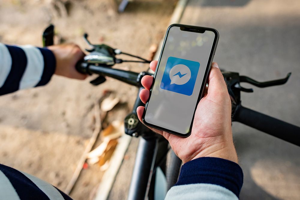 Cyclist using Facebook Messenger application on a phone. BANGKOK, THAILAND, 1 NOV 2018.