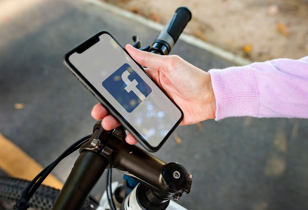 Cyclist using Facebook application on a phone. BANGKOK, THAILAND, 1 NOV 2018.