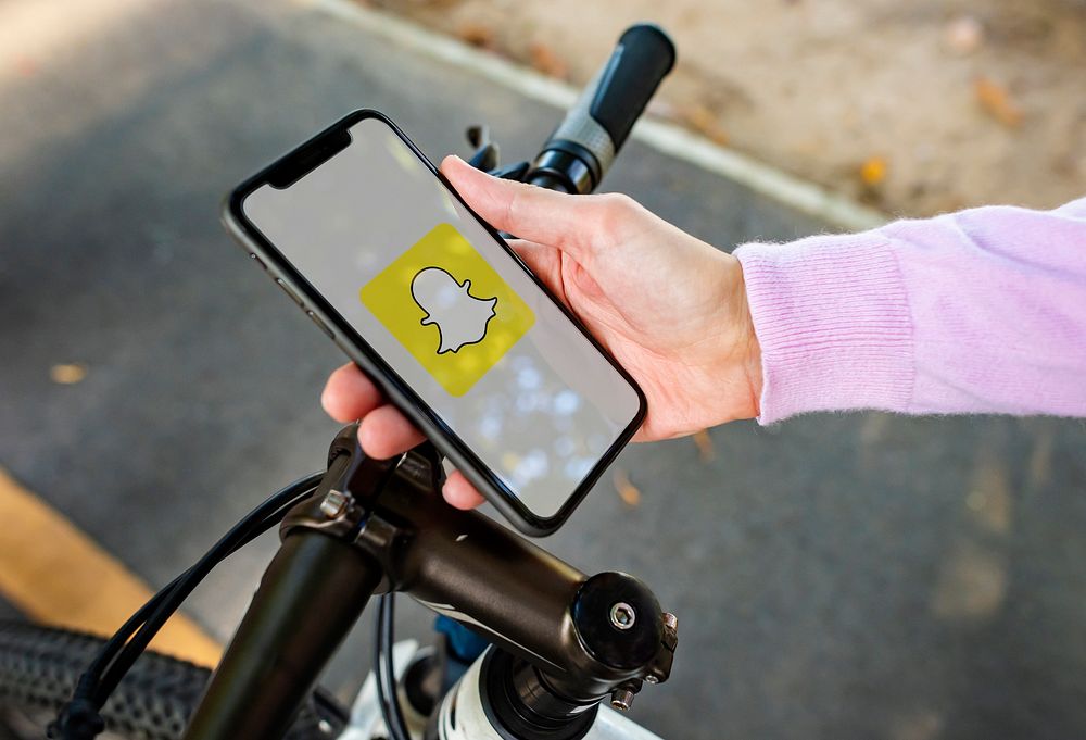 Cyclist using Snapchat on a phone. BANGKOK, THAILAND, 1 NOV 2018.