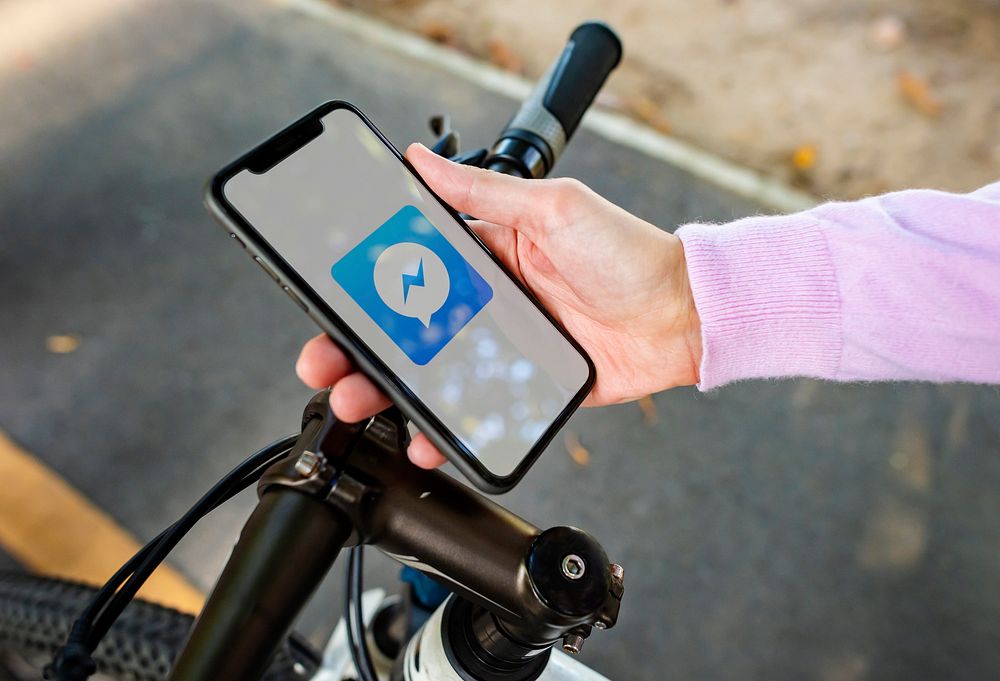 Cyclist using Facebook Messenger application on a phone. BANGKOK, THAILAND, 1 NOV 2018.