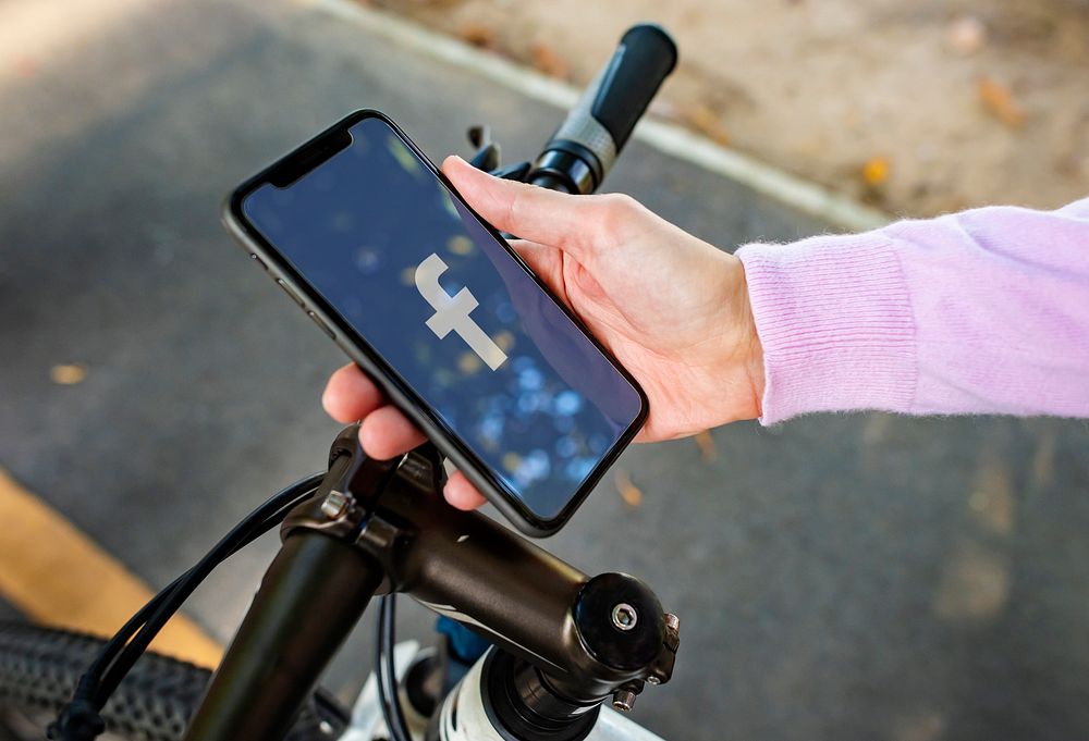 Cyclist using Facebook application on a phone. BANGKOK, THAILAND, 1 NOV 2018.