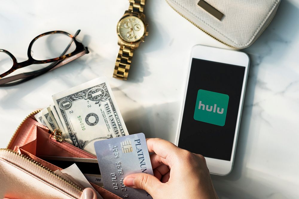 Hand getting a credit card while Hulu logo showing on a phone. BANGKOK, THAILAND, 1 NOV 2018.