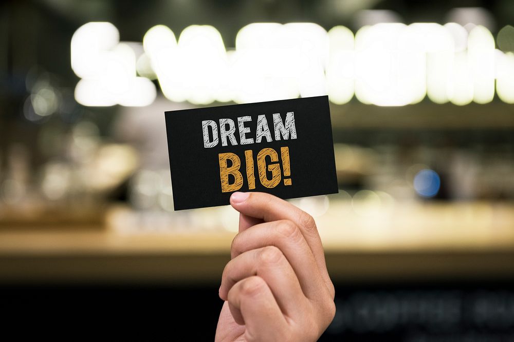Hand holding a black paper card with Dream big wording
