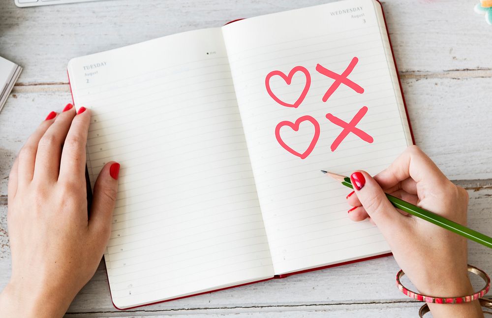Woman drawing hearts and kisses symbols on a notebook