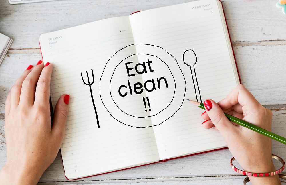 Woman writing Eat clean on a notebook