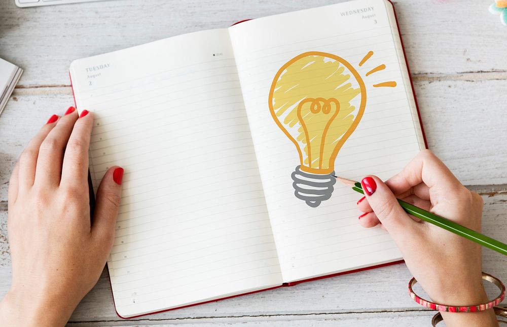 Woman drawing a light bulb on a notebook