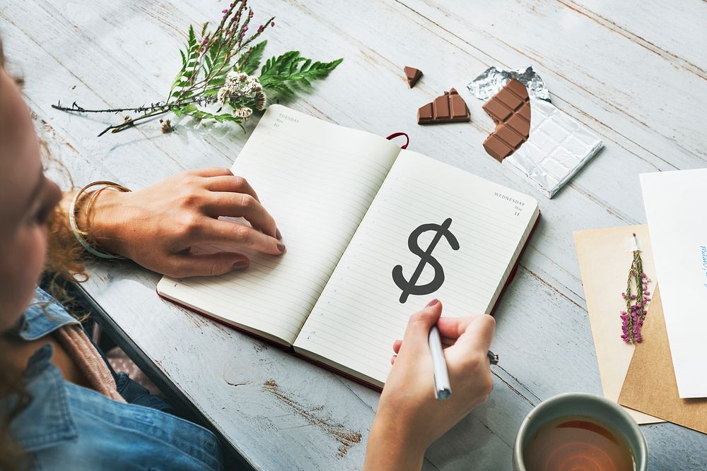 Woman drawing a dollar sign on a notebook