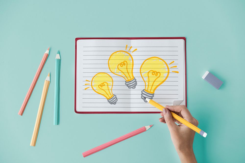 Hand drawing light bulbs on a notebook