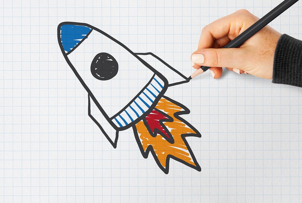 Hand drawing a rocket launch on a notebook paper