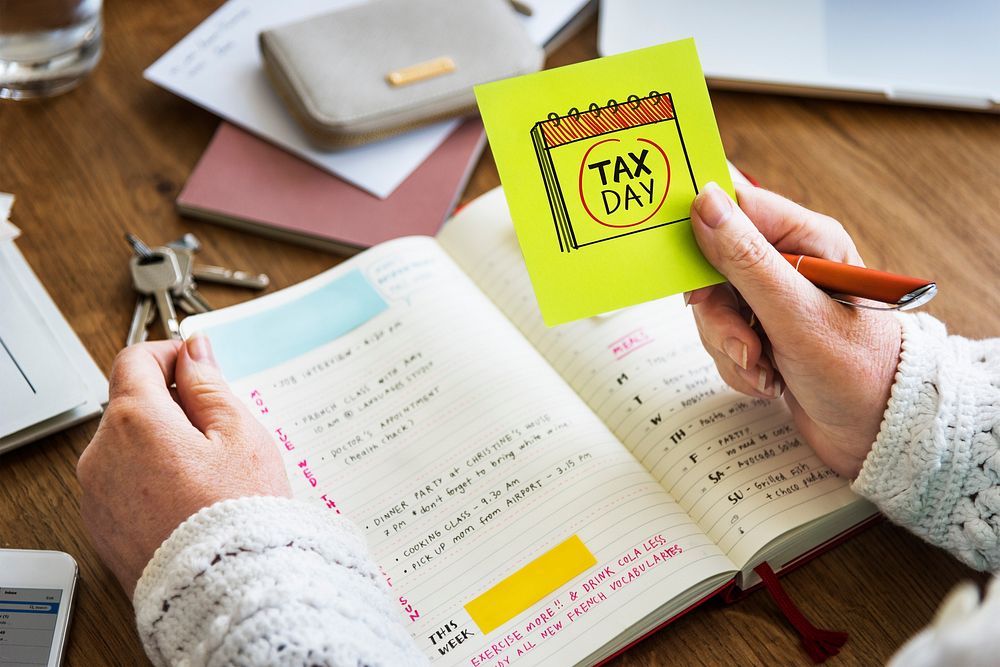 Woman holding a sticky note with tax day circled