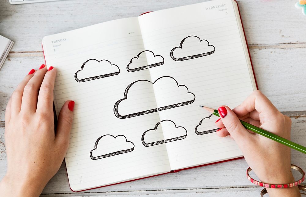 Young woman drawing clouds in a notebook