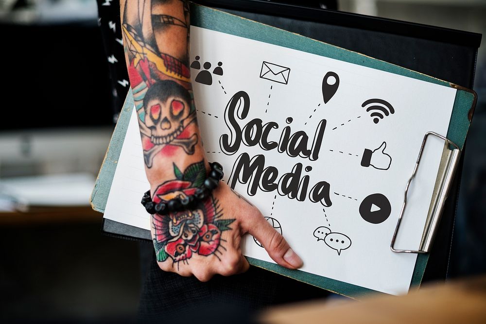Tattooed hand holding a social media clipboard