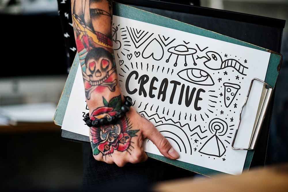 Tattooed hand holding a creative clipboard