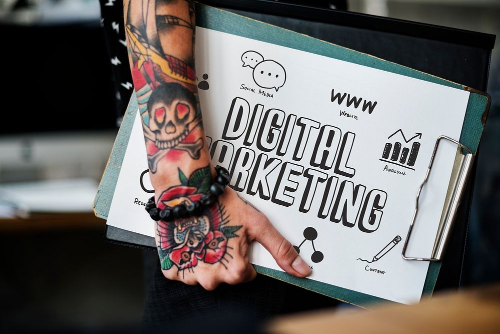 Tattooed hand holding a digital marketing clipboard