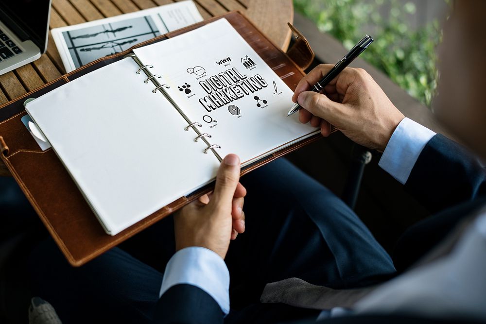 Businessman writing a digital marketing plan in a notebook