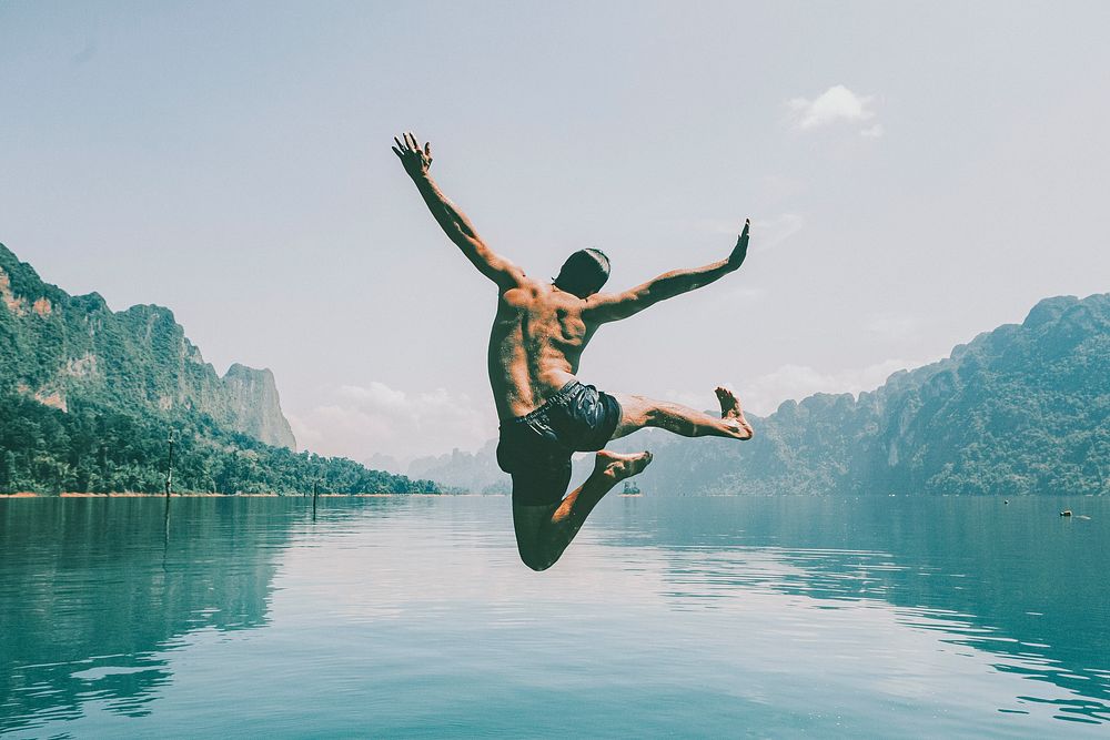 Wanderlust desktop wallpaper background, man jumping with joy by a lake, vintage tone