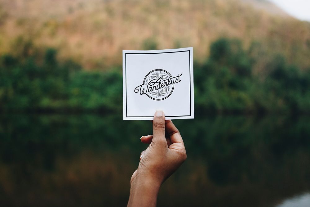 Traveler holding up a note in nature mockup