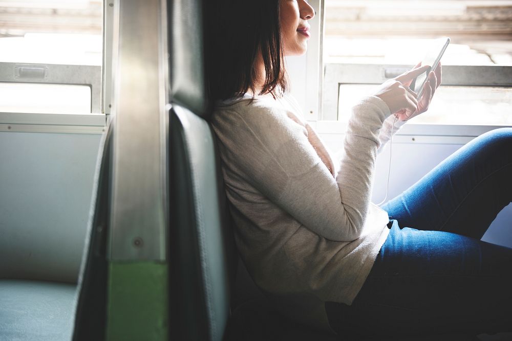Asian woman sitting in a train using mobile phone