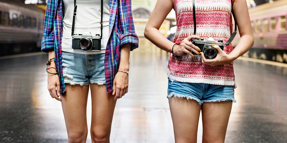 Two tourist women standing at train platform with camera