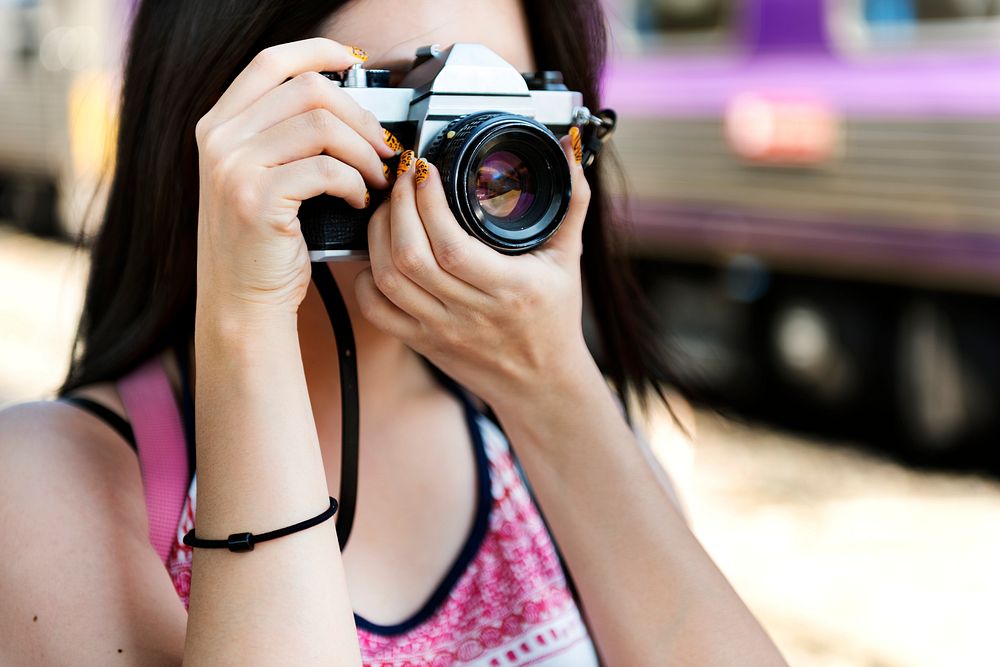 Young woman is taking photo with film camera