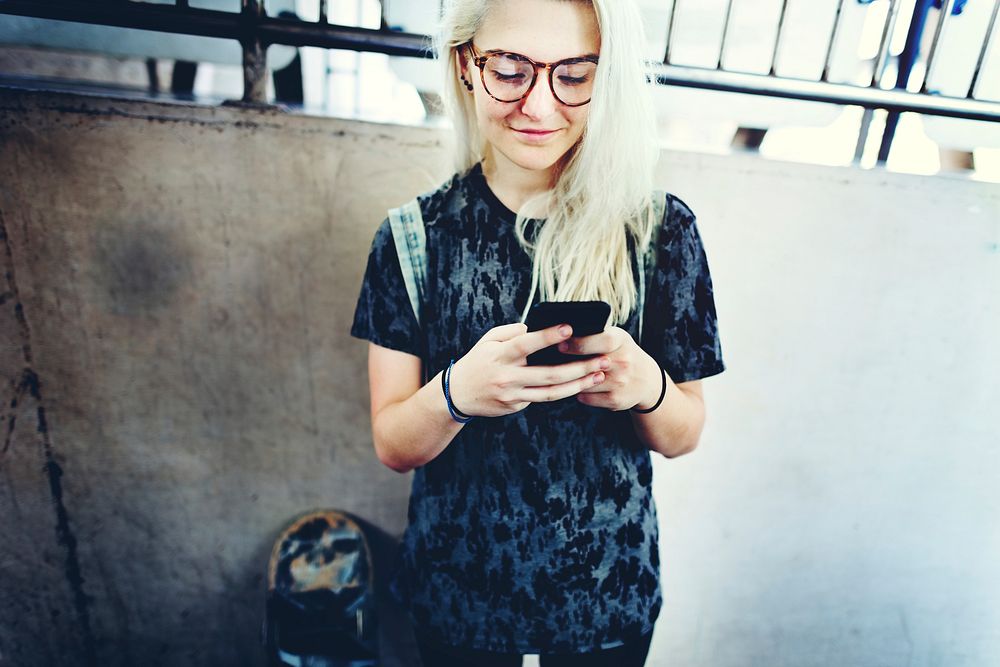 Young Woman Skater Browsing Phone Concept