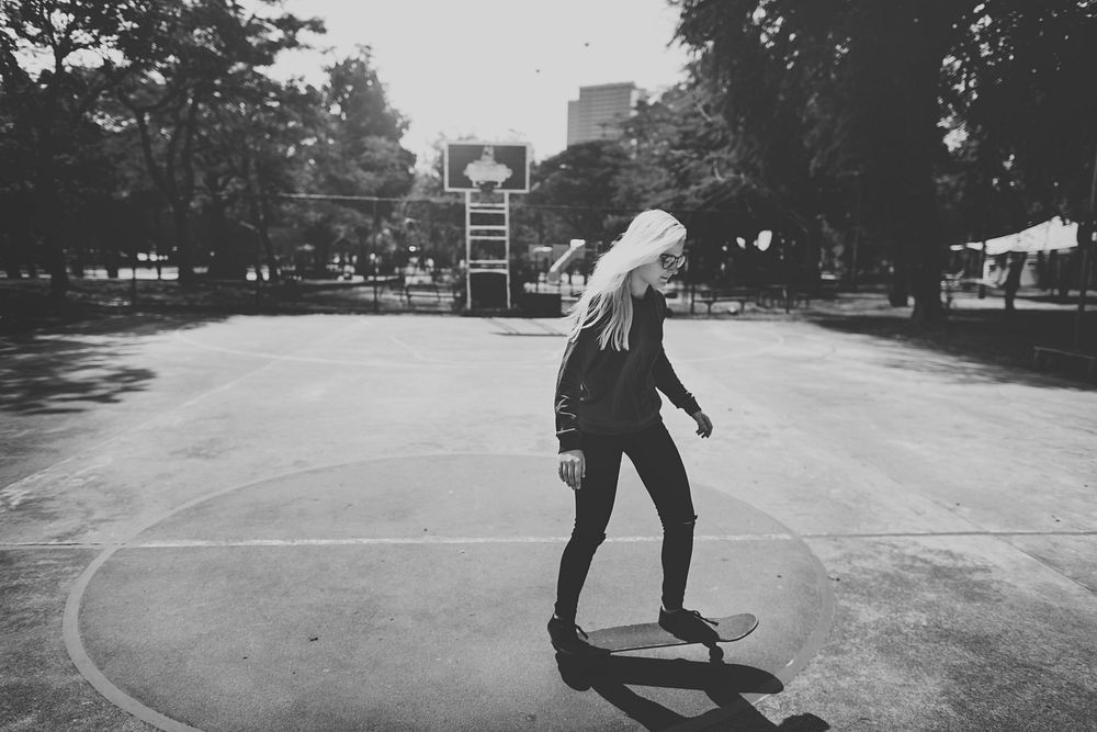 Woman playing skateboard in basketball court