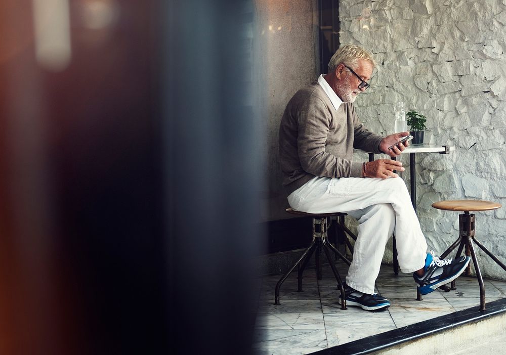 Senior caucasian man using mobile phone at cafe ourdoors