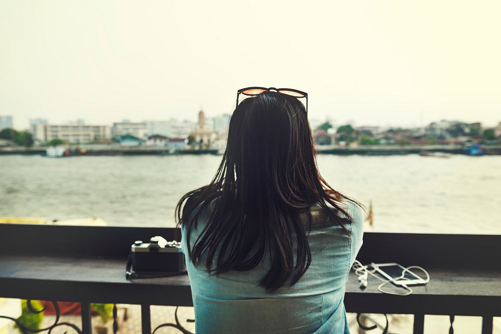 Rear view of asian tourist woman sitting by the riverside