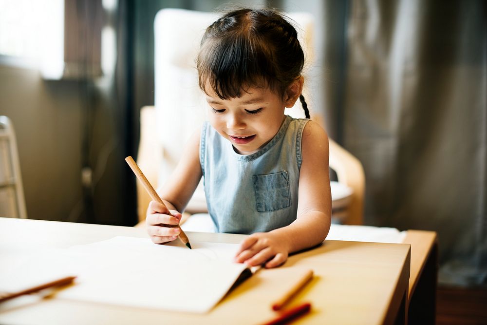 Little girl drawing in a book